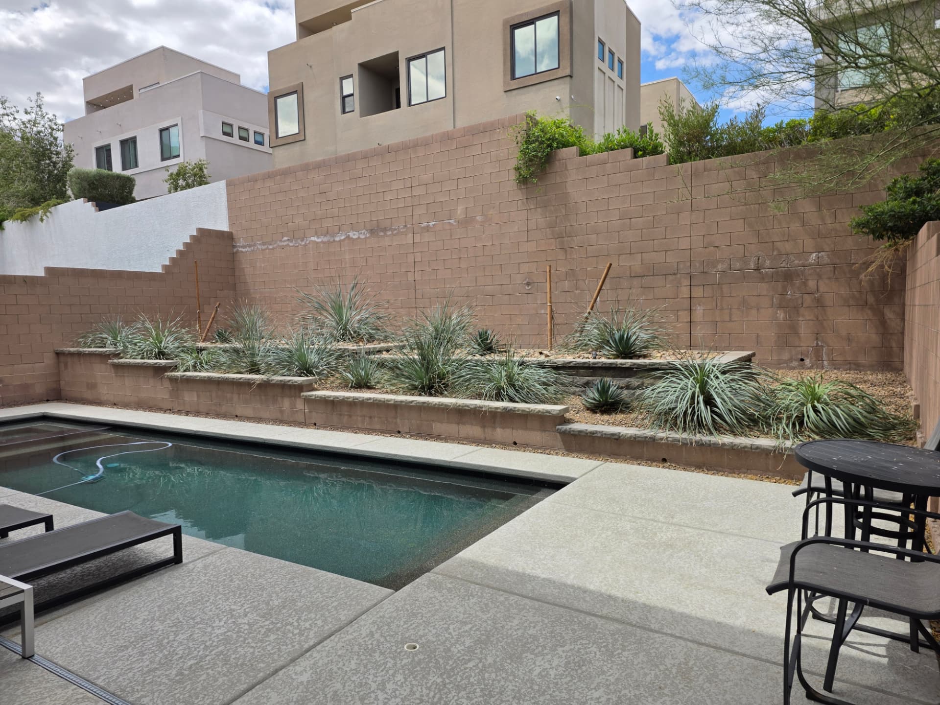 The same poolside planters and block wall open to the sky after mesquite removal